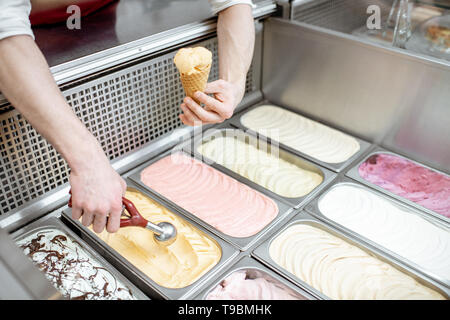 Vassoi di metallo piena di colorati gelato nella vetrina frigorifero, venditore tenuto gelati con convogliatore, vista da vicino Foto Stock