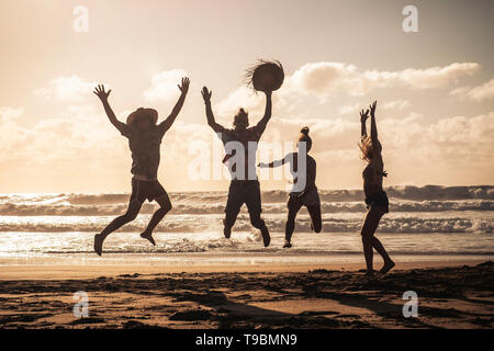 Tramonto sulla spiaggia con felice del gruppo di giovani persone che saltano divertendosi - amici su vacanze estate vacanze godendo insieme in amicizia - sandy l Foto Stock