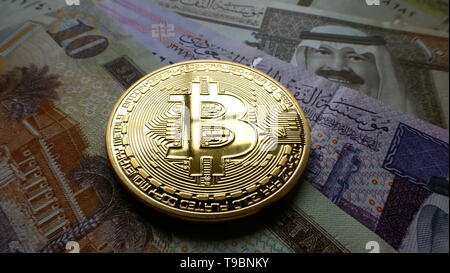 Bitcoin, una moneta virtuale in moneta fisica forma, visualizzato su Saudi Arabian Riyal banconote Foto Stock