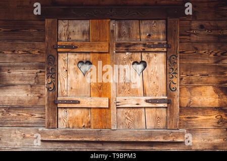 Vecchie finestre in legno di una casa in legno con due intagli di cuori Foto Stock