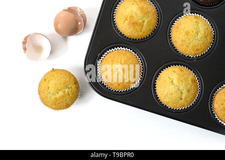 Cotto al forno cupcake dolci in un muffin di stagno e di gusci d'uovo isolato con ombre su uno sfondo bianco, ad alto angolo di vista da sopra lo spazio di copia Foto Stock