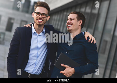 Due colleghi sorridente parlando e divertirsi a street. Foto Stock