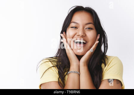 La ragazza di amore con il proprio corpo e le imperfezioni essendo unbothered positivo dell'acne e delle cicatrici toccando le guance e sorridente largamente lieto e spensierato, posa Foto Stock