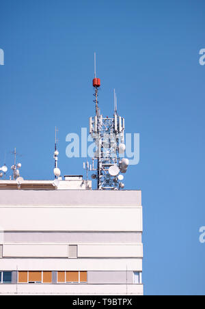 Telecomunicazioni stazioni base di ripetitori di rete sul tetto dell'edificio. La comunicazione cellulare Antenna sul city building tetto. Foto Stock