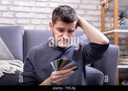 Ha sottolineato l'uomo Guardando troppo molte carte di credito in Home Foto Stock