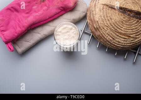 Vista superiore della pasta madre il lievito in un vaso accanto a un pane appena sfornato pane fatto in casa. Foto Stock