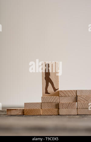 Mattoni di legno sul tavolo con forma di uomo a camminare su per le scale. Carriera la concezione di business. Spazio di copia Foto Stock