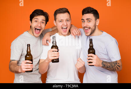Hurray, weekend! Uomini che tengono le bottiglie di birra, sfondo arancione Foto Stock