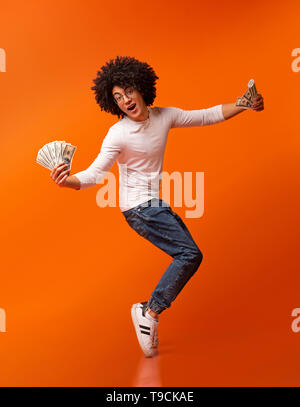 Felice African American guy dancing sulla tiptoes con ventole di denaro Foto Stock