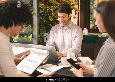 Soddisfatto l uomo la lettura di grandi notizie su laptop durante il pranzo di lavoro Foto Stock