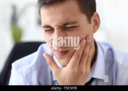 Giovane imprenditore che soffrono di mal di denti in office Foto Stock