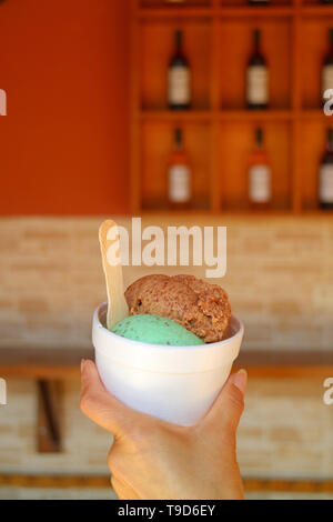 Donna di mano che regge due mestoli di lucuma frutta e mint choc chip coppa di gelato, regione di Ica, Perù Foto Stock