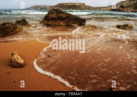 Onde sulla spiaggia in Malta. Una vista della spiaggia, il mare e le sue coste in Gnejna Bay, Malta. Foto Stock