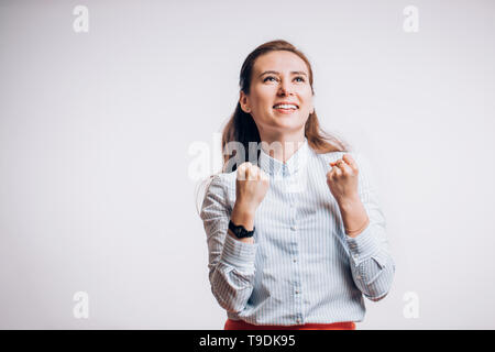 Ritratto di contentissimo clenches femmina a pugni con la felicità. Donna felice con gioiosa espressione su uno sfondo bianco con spazio di copia Foto Stock