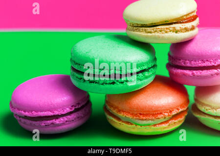 Primo piano colorato di rosa, arancione, verde. francesi beige amaretti dolce sul tavolo. Foto macro torte Foto Stock