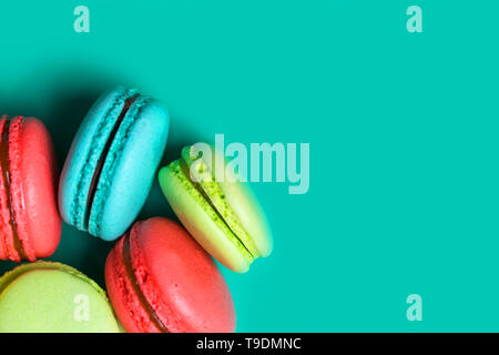Close up di freschi e deliziosi amaretti su sfondo turchese con copia spazio per pasticceria, caffetteria e pasticceria Foto Stock