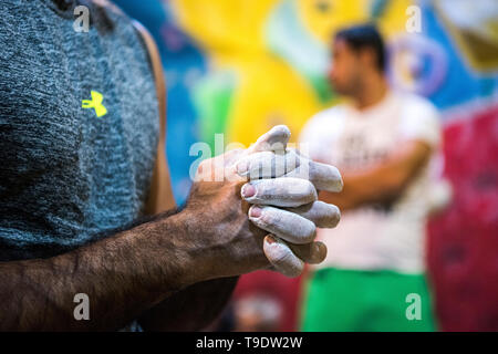 Un scalatore di mano piena di arrampicata chalk e parete di arrampicata sullo sfondo. Foto Stock