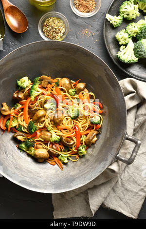 Mescolare le verdure fritte con tagliatelle in padella wok su pietra nera dello sfondo. Vista superiore, laici piatta Foto Stock