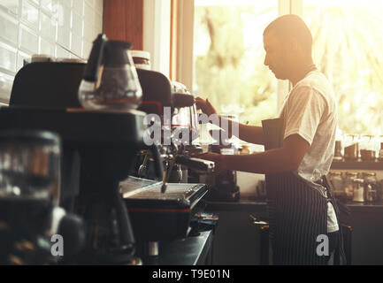 Barista prepara il cappuccino nel suo negozio di caffè Foto Stock