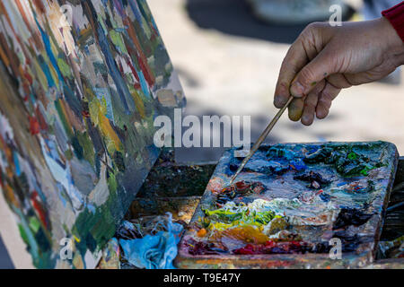 Primo piano di un irriconoscibile uomo con gli artisti e la tavolozza di colori di miscelazione mentre la pittura Foto Stock