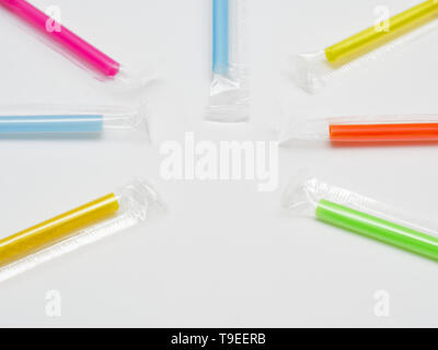 Molti multicolore di cannucce di plastica formando un cerchio. Isolato su sfondo bianco con spazio vuoto per la didascalia. Cannucce di plastica sono vietate in vario Foto Stock