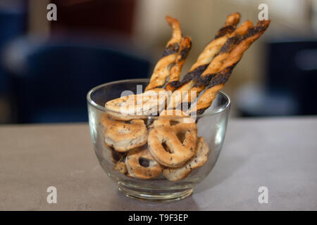 Torte salate di bagel e bastoni in una ciotola di vetro al tavolo bar e sfondo sfocato. Parte il concetto di cibo. Close up, il fuoco selettivo Foto Stock