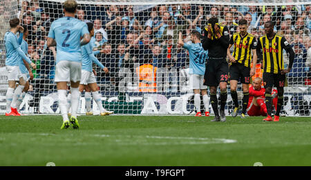 Londra, Regno Unito. 18 Maggio, 2019. Watford i giocatori di sguardo sconsolato come Manchester City i giocatori di celebrare dopo rigature durante la FA Cup inglese finale tra Manchester City e Watford allo Stadio di Wembley a Londra, Gran Bretagna il 18 maggio 2019. Il Manchester City ha vinto 6-0 e divenne il primo inglese uomini di lato per realizzare la prodezza di vincere la Premier League, FA Cup e Coppa Carabao nella stessa stagione. Credito: Han Yan/Xinhua/Alamy Live News Foto Stock