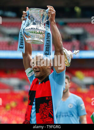 Londra, Regno Unito. 18 Maggio, 2019. Manchester City's Vincent Kompany celebra con il trofeo come il coperchio del trofeo scende da dietro dopo aver vinto la FA Cup inglese finale tra Manchester City e Watford allo Stadio di Wembley a Londra, Gran Bretagna il 18 maggio 2019. Il Manchester City ha vinto 6-0 e divenne il primo inglese uomini di lato per realizzare la prodezza di vincere la Premier League, FA Cup e Coppa Carabao nella stessa stagione. Credito: Han Yan/Xinhua/Alamy Live News Foto Stock