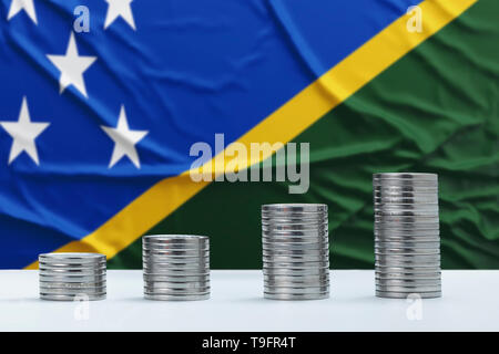 Stropicciata Isole Salomone bandiera in background con righe di monete per la finanza e per il concetto di business. Risparmio di denaro. Foto Stock