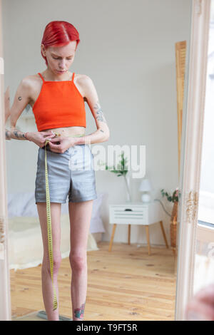 Skinny donna misurando il suo girovita con nastro di misurazione Foto Stock