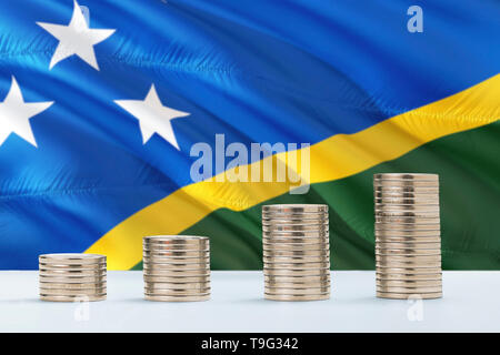 Isole Salomone bandiera sventola in background con righe di monete per la finanza e per il concetto di business. Risparmio di denaro. Foto Stock