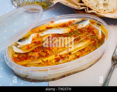 Conserve di sardine marinate con spezie in contenitore di plastica Foto Stock