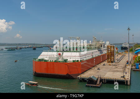 Bali, Indonesia - 25 Febbraio 2019: il bianco e il rosso deposito galleggiante e unità di rigassificazione, FSRU, LNG-nave nel porto di Benoa sotto luce blu del cielo. Foto Stock