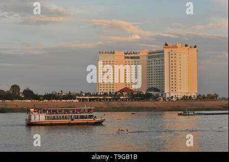 Il traffico fluviale sul fiume Tonle Sap al tramonto, il Sokha Hotel in background, Phnom Penh Cambogia. Credito: Kraig Lieb Foto Stock