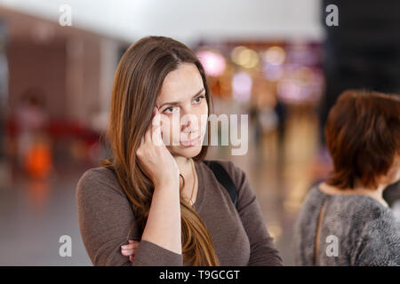Giovane donna con mal di testa in attesa in coda. Foto Stock