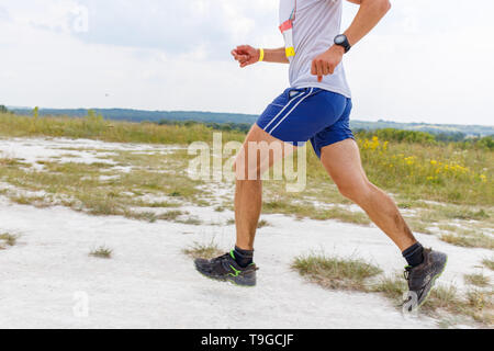 Chiudere l immagine di gambe di uomo in esecuzione su suolo sabbioso Foto Stock