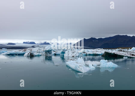 Jokulsarlon laguna glaciale, Islanda al tramonto. Bellissimi ghiacciai fluiscono attraverso le montagne. Paesaggio freddo foto del ghiacciaio islandese lagoon bay. Foto Stock