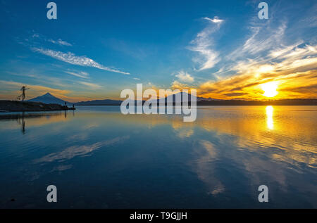 Sunrise in Puerto Varas con una vista sull'Osorno e Calbuco vulcano così come i pescatori locali sagome, Lago Llanquihue, Cile. Foto Stock