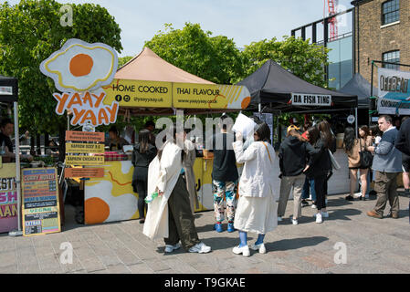 Bancarelle prodotti alimentari compresi Yaay Yaay e da pesce Ting con persone davanti il granaio di accodamento Square Kings Cross, London Borough of Camden Inghilterra Gran Bretagna REGNO UNITO Foto Stock