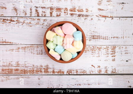 Marshmallows in una ciotola rotonda bianca su sfondo di legno. Vista dall'alto. Foto Stock