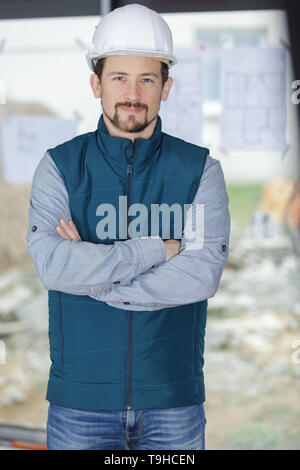 Sorridente barbuto lavoratore in tuta in posa con bracci incrociati Foto Stock