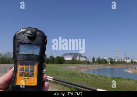 Vista del reattore 4 da una distanza di sicurezza con un contatore Geiger, all'interno della centrale di Cernobil zona di esclusione, Ucraina Foto Stock