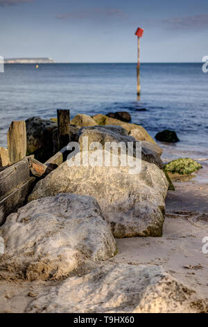 Groyne con rocce e un marcatore di post in mare presso la spiaggia di Avon Mudeford con Isle of Wight a distanza Foto Stock