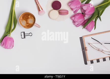 Di un bel colore rosa tulipani, una tazza di caffè e macaron sul tavolo bianco, vista dall'alto Foto Stock