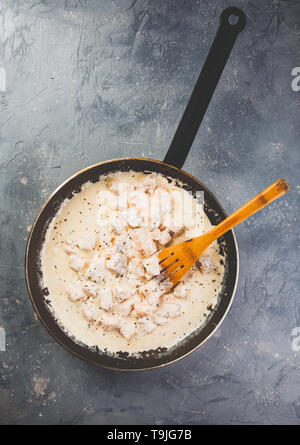 A cubetti di salmone sono fritte in crema di latte in una padella. Vista dall'alto. Foto Stock