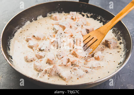 A cubetti di salmone sono fritte in crema di latte in una padella Foto Stock