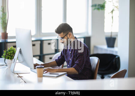 Bel giovane uomo d affari con il luogo di lavoro in ufficio creativo Foto Stock