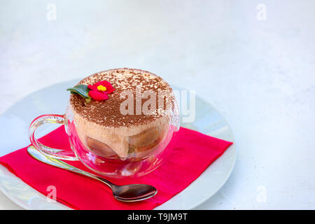 Famoso caffè Tiramisù decorate con cacao Cioccolata fiore in vetro - popolare italiana tradizionale dessert con crema di mascarpone, liquore caffè espresso Foto Stock