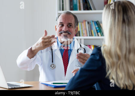 Ridere medico spiegando il trattamento medico al paziente di sesso femminile all'ospedale Foto Stock