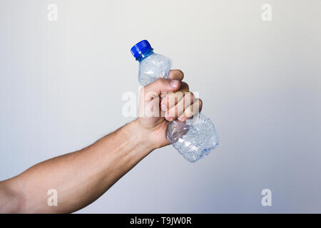 Spremitura a mano la bottiglia di plastica che rappresentano il movimento contro l'inquinamento e per il riciclaggio. Foto Stock
